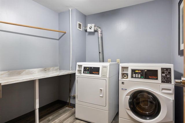 community laundry room with separate washer and dryer and wood finished floors