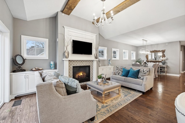 living room featuring lofted ceiling with beams, dark wood-style flooring, a tiled fireplace, and a chandelier