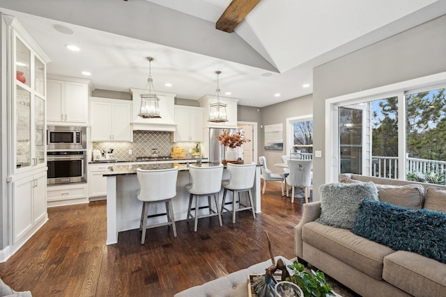 kitchen featuring tasteful backsplash, a breakfast bar, premium range hood, appliances with stainless steel finishes, and open floor plan