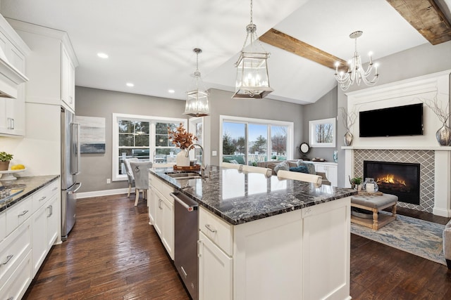 kitchen with a sink, stainless steel appliances, open floor plan, dark wood finished floors, and a notable chandelier