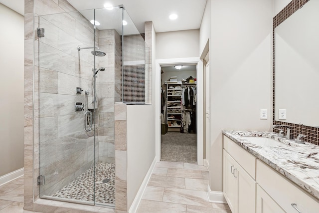 full bath featuring a shower stall, marble finish floor, vanity, baseboards, and a spacious closet
