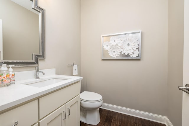 bathroom with baseboards, wood finished floors, toilet, and vanity