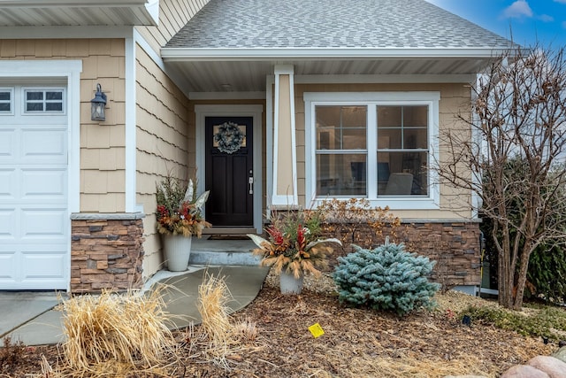 view of exterior entry featuring a porch, stone siding, an attached garage, and roof with shingles