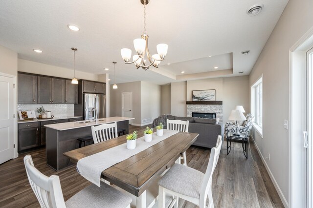 dining area featuring recessed lighting, a chandelier, dark wood-style flooring, a fireplace, and baseboards