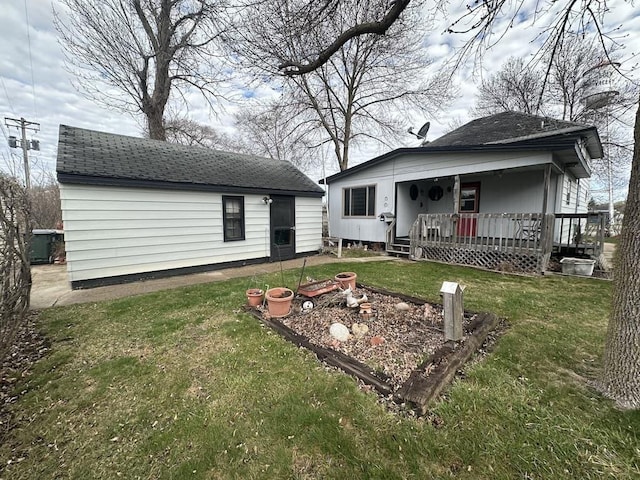 rear view of property featuring a lawn, covered porch, and roof with shingles