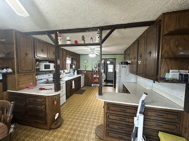 kitchen featuring a textured ceiling, light countertops, dark brown cabinetry, white appliances, and a ceiling fan