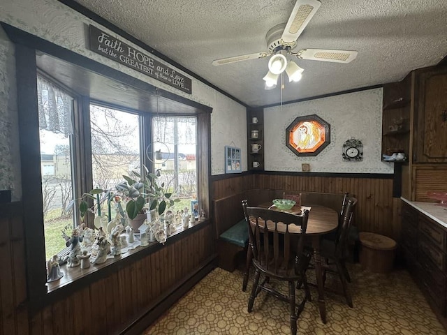 dining area featuring a healthy amount of sunlight, wood walls, a wainscoted wall, and a textured ceiling