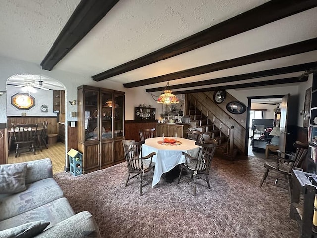 dining space with wood walls, a wainscoted wall, a textured ceiling, and ceiling fan
