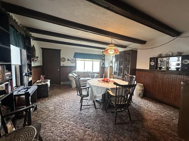 dining area with wood walls, beamed ceiling, a wainscoted wall, and carpet flooring