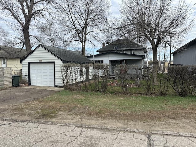 view of front facade featuring an outdoor structure, aphalt driveway, fence private yard, and a garage