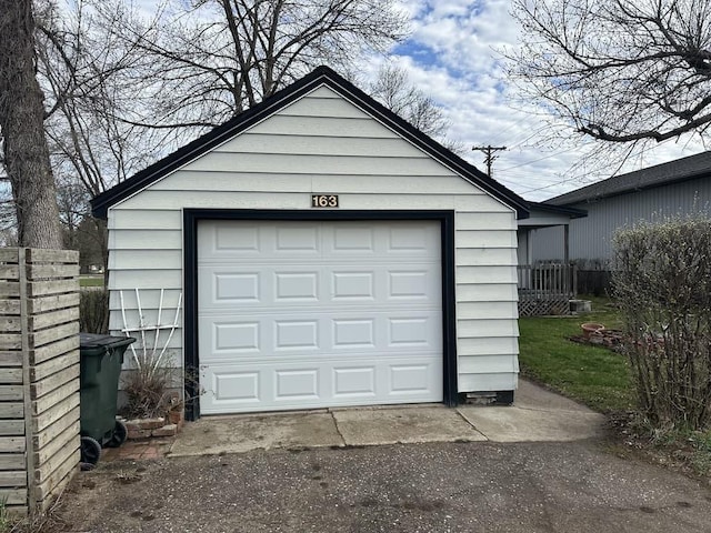detached garage featuring fence and aphalt driveway