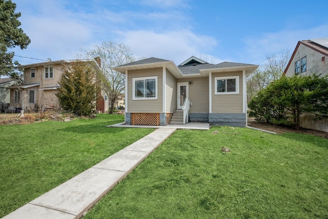 bungalow-style home with entry steps, a shingled roof, and a front lawn