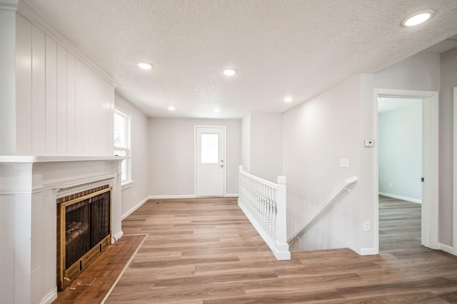 interior space featuring a textured ceiling, baseboards, and light wood-style flooring