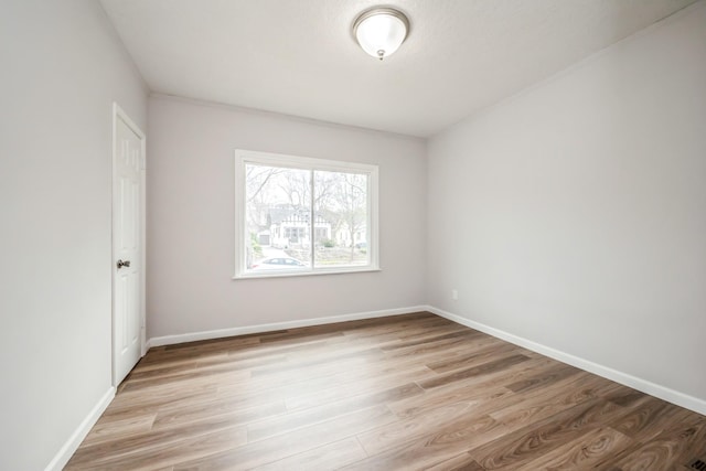 unfurnished room with light wood-type flooring and baseboards