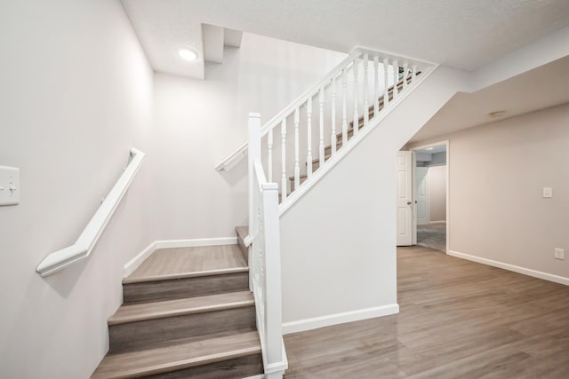 stairway with baseboards and wood finished floors