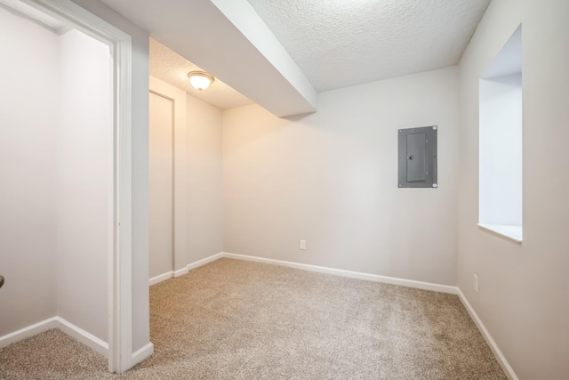 below grade area featuring baseboards, carpet flooring, a textured ceiling, and electric panel