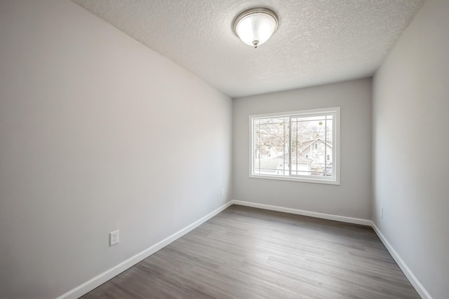 spare room featuring baseboards, a textured ceiling, and wood finished floors