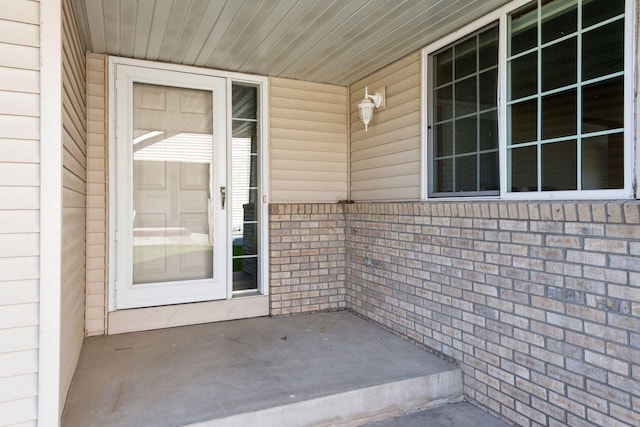 entrance to property with a porch and brick siding