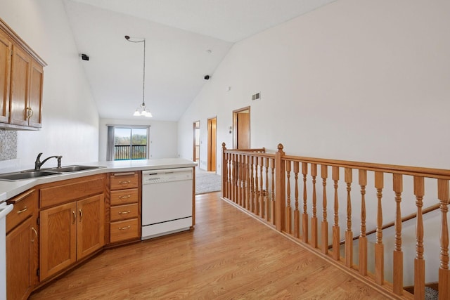 kitchen with a sink, dishwasher, a peninsula, light wood-type flooring, and pendant lighting