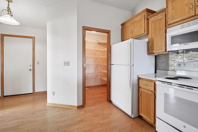 kitchen featuring white appliances, light countertops, tasteful backsplash, light wood finished floors, and hanging light fixtures