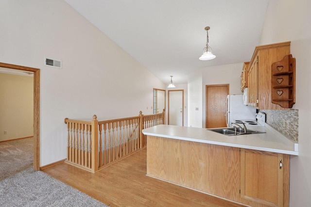 kitchen featuring a sink, light countertops, a peninsula, decorative light fixtures, and visible vents
