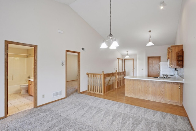 kitchen featuring decorative light fixtures, light colored carpet, high vaulted ceiling, and visible vents