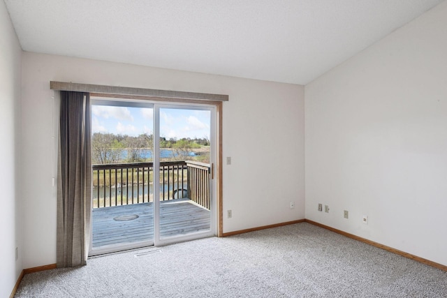 carpeted empty room with a water view and baseboards