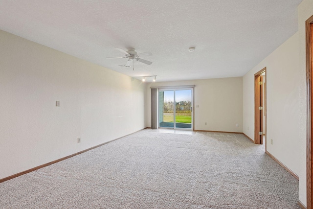 empty room featuring baseboards, a ceiling fan, a textured ceiling, and light carpet