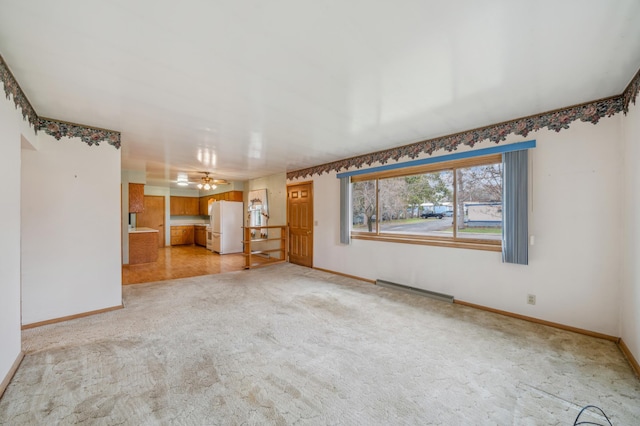 unfurnished living room with light carpet, baseboard heating, and baseboards