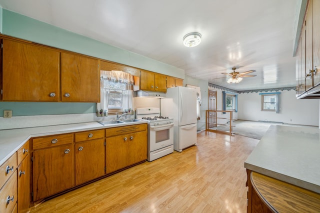 kitchen featuring a sink, brown cabinets, ceiling fan, white appliances, and light countertops