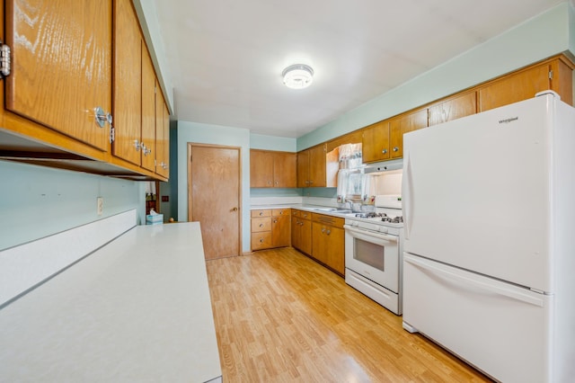 kitchen featuring a sink, light wood-style floors, light countertops, white appliances, and brown cabinetry