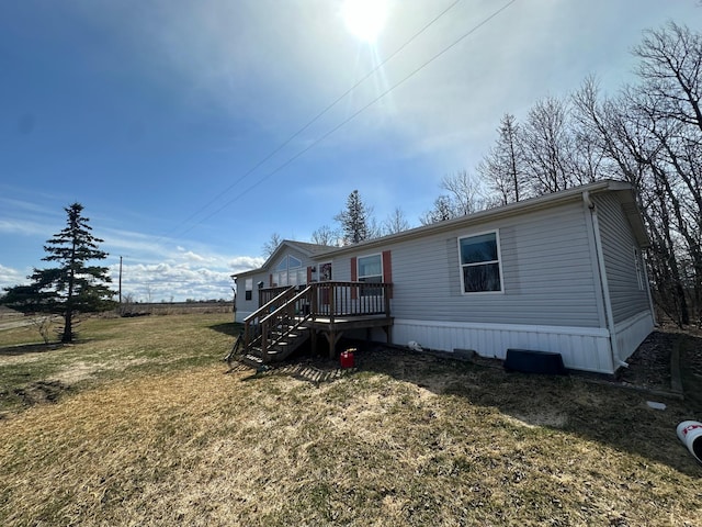manufactured / mobile home with a front lawn, a wooden deck, and stairs