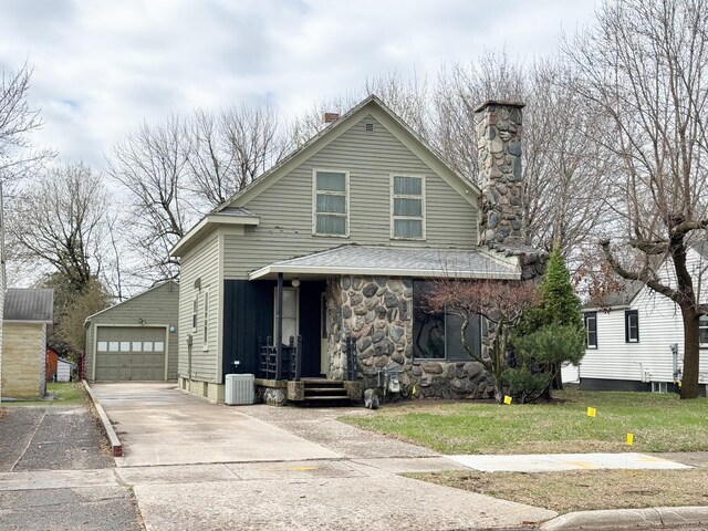 view of front facade with a chimney, an outbuilding, driveway, a detached garage, and central AC unit