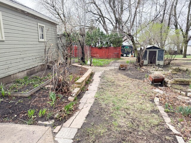 view of yard with a garden, a shed, fence, and an outdoor structure