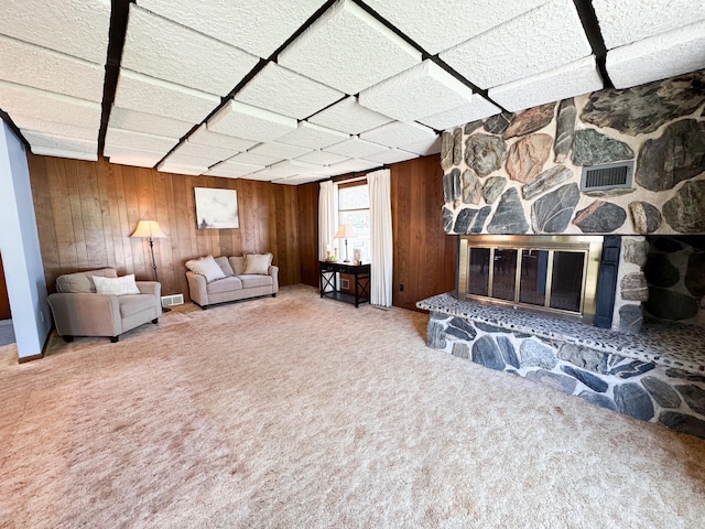 living area with wooden walls, carpet flooring, and a fireplace