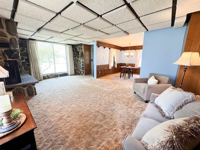carpeted living area featuring a chandelier and a wainscoted wall