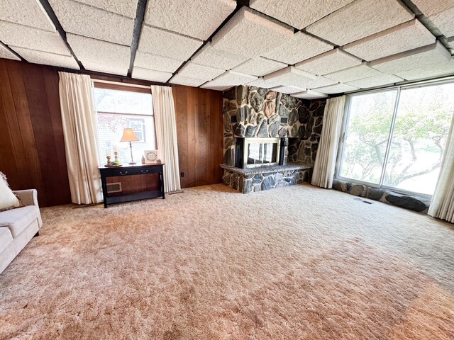 unfurnished living room with wood walls, healthy amount of natural light, carpet floors, and a fireplace