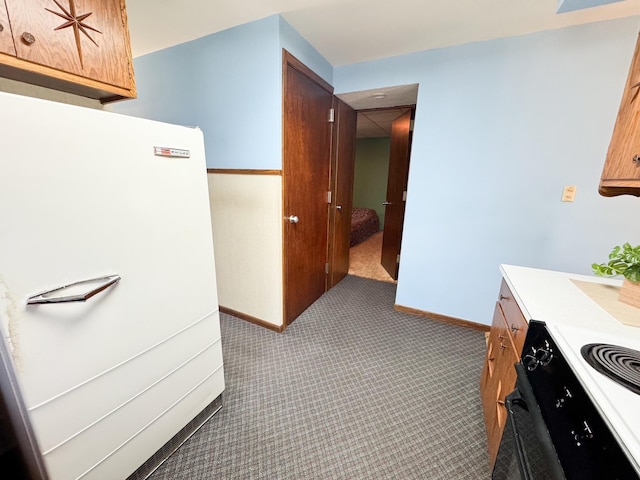 kitchen featuring black / electric stove, light carpet, freestanding refrigerator, and light countertops