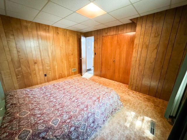 bedroom featuring carpet floors, wood walls, and a drop ceiling