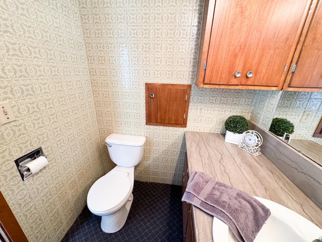 bathroom featuring toilet and wallpapered walls