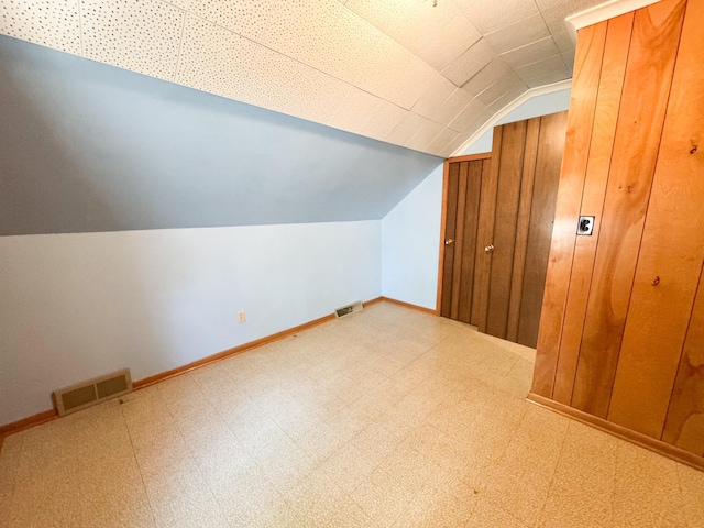 bonus room featuring lofted ceiling, tile patterned floors, and baseboards