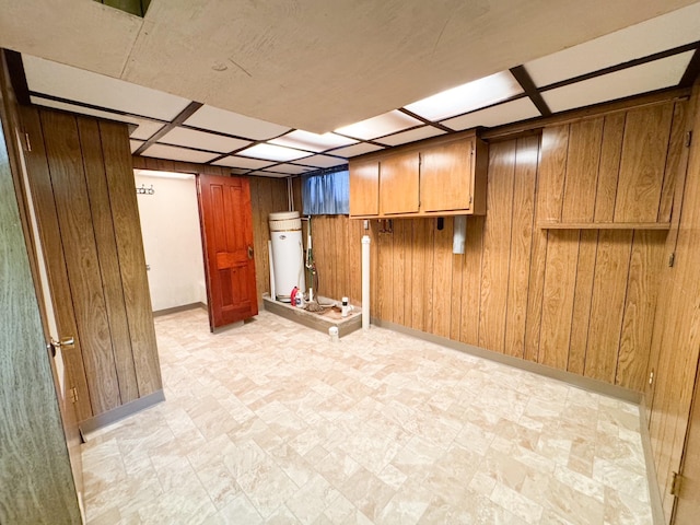 finished basement featuring wooden walls, baseboards, and light floors