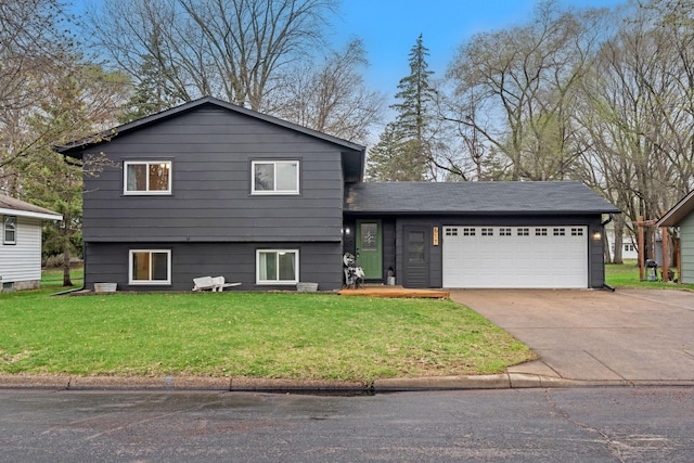 split level home with concrete driveway, an attached garage, and a front lawn