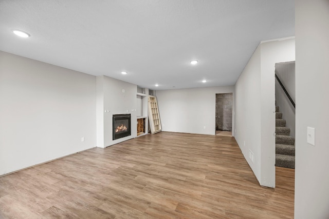 426 Dillon Ave N, Montrose, MN 55363 - unfurnished living room with a glass covered fireplace, light wood-style floors, recessed lighting, and stairway