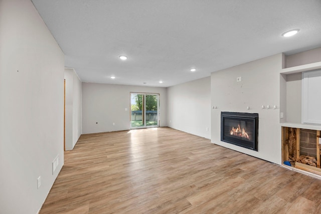 426 Dillon Ave N, Montrose, MN 55363 - unfurnished living room featuring a glass covered fireplace, light wood-style flooring, and recessed lighting