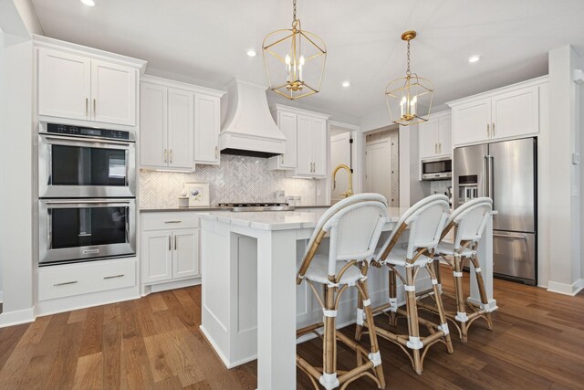 10859 23rd St NE, Saint Michael, MN 55376 - kitchen with appliances with stainless steel finishes, custom range hood, decorative backsplash, a kitchen island with sink, and dark wood-style flooring