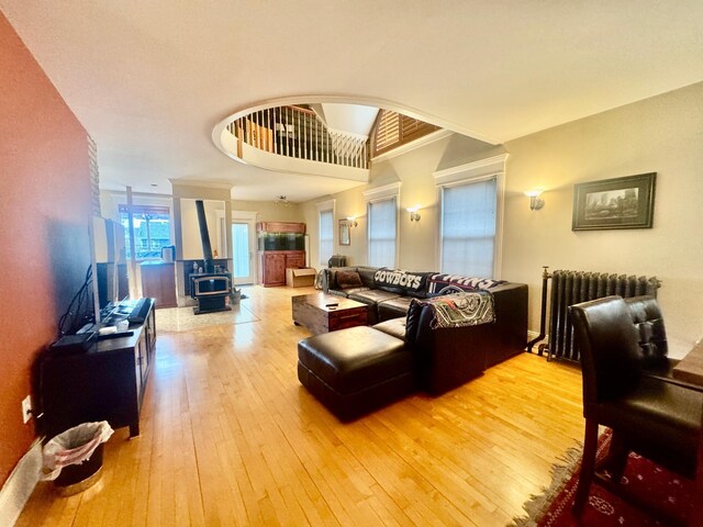 living area featuring a wood stove, radiator heating unit, and hardwood / wood-style floors