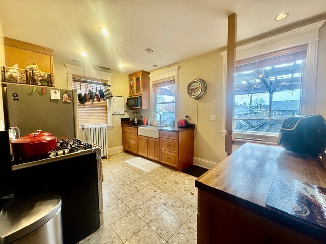 kitchen featuring black microwave, a sink, baseboards, freestanding refrigerator, and radiator heating unit