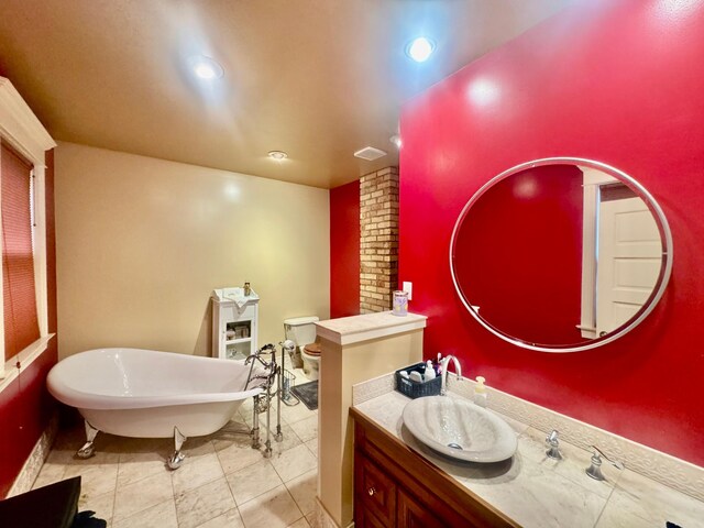 bathroom featuring decorative columns, a freestanding tub, baseboards, vanity, and recessed lighting