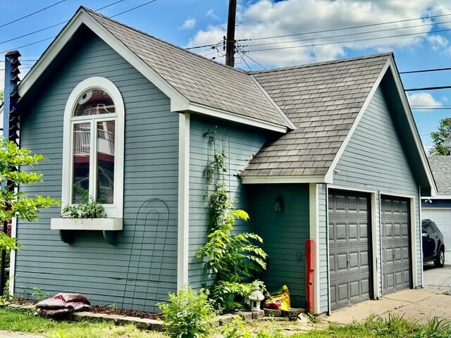 view of side of home with a garage and a shingled roof
